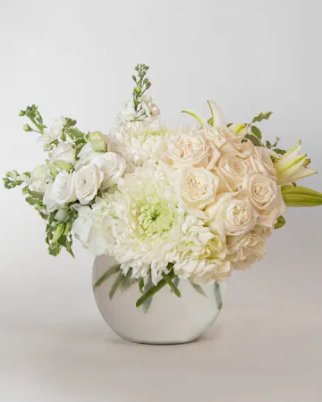 Beautiful roses are arranged in an elegant cylinder glass leaf-lined vase. 