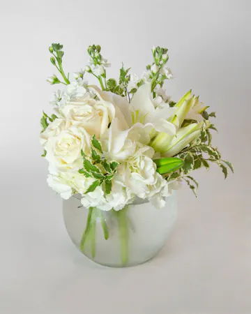 Beautiful roses are arranged in an elegant cylinder glass leaf-lined vase. 