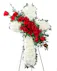The Devotion Cross features white carnations arranged to form a cross with an accent of red roses and lush greens that are draped across the center. 