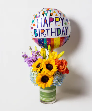 colorful bouquet with hydrangea, sunflowers, roses, asiatic lilies, and lisianthus in a tall cylinder glass leaf-lined vase, and comes with a fun birthday mylar balloon