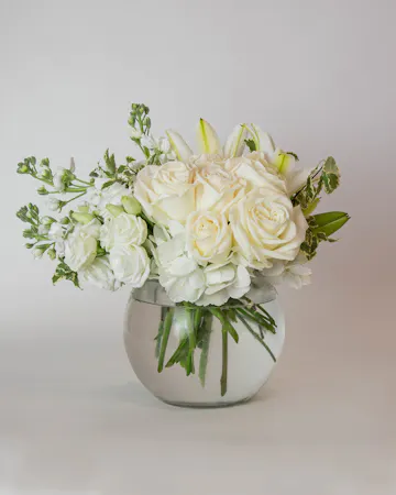 Beautiful roses are arranged in an elegant cylinder glass leaf-lined vase. 