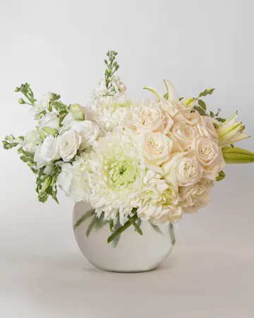 Beautiful roses are arranged in an elegant cylinder glass leaf-lined vase. 