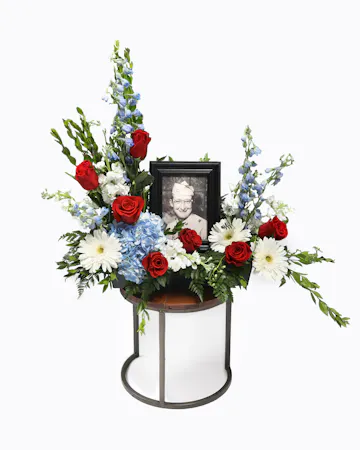 Surround the photo of your loved one with red, white, and blue florals, the arrangement will bring comfort and peace to their family and friends during a time of loss.