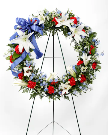A stunning display of patriotism, strength, and sympathy. This red, white, and blue fresh floral wreath delivers a lovely message about the dignity of the deceased.