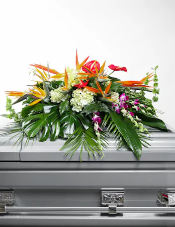 An overflow of love and respect is joyfully expressed in this tropical casket spray to celebrate the life of a loved one who has recently passed.
