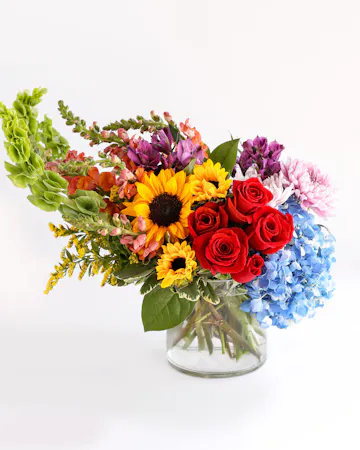 Flirty 30s boasts a beautiful blend of colorful roses, sunflowers, cremones, and hydrangeas, with each flower completing the other perfectly. 