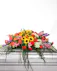 This vibrant and full casket spray is filled with bright blooming flowers.