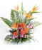 A vibrant floral arrangement featuring orange bird-of-paradise flowers and purple orchids, surrounded by large green leaves, placed on a white surface.