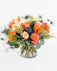 An orange tropical flower arrangement featuring birds of paradise, thistle, and roses. 