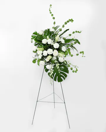 This display of white blooms is artfully arranged amongst lush greenery creating an outstanding way to honor the life of your loved one. 