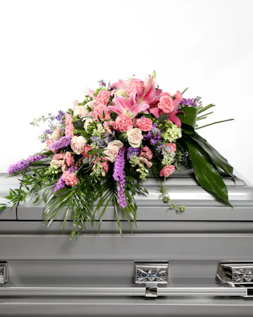 This pink and purple mixed casket spray lays beautifully atop of a casket like a handheld bouquet to pay tribute to your loved one.