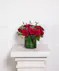 Beautiful roses are arranged in an elegant cylinder glass leaf-lined vase. 