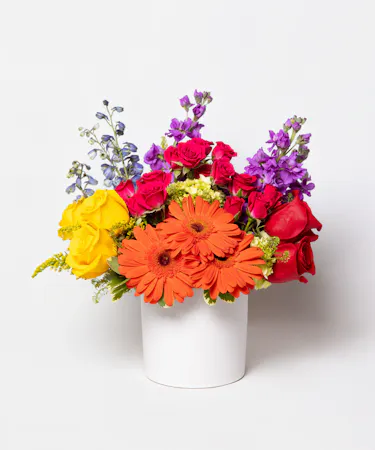 This colorful array of roses, gerbera daisies, delphinium, spray roses and more is sure to bring a smile to anyone's face.