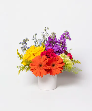 This colorful array of roses, gerbera daisies, delphinium, spray roses and more is sure to bring a smile to anyone's face.
